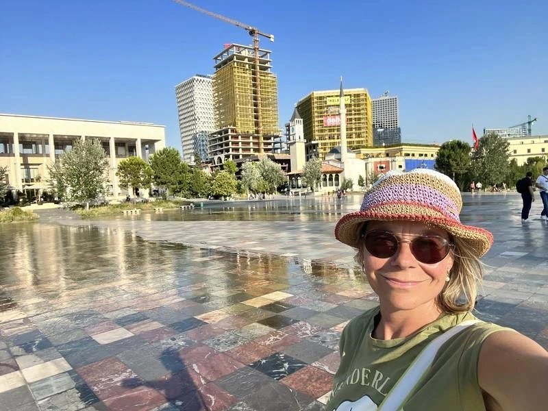 Frau mit buntem Hut und Sonnenbrille macht Selfie auf Skanderbeg Platz, Tirana, Albanien