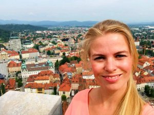 Selfie einer lächelnden Frau mit Blick auf eine Stadt mit roten Dächern und Bergen im Hintergrund in Ljubljana Slowenien