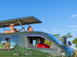Reisende schauen aus der offenen Dachluke im Minivan in Tansania