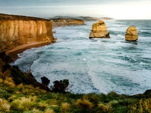 Panoramablick auf die Twelve Apostles in Australien mit zwei markanten Felsformationen, goldenen Klippen und schäumenden Meereswellen in Australien
