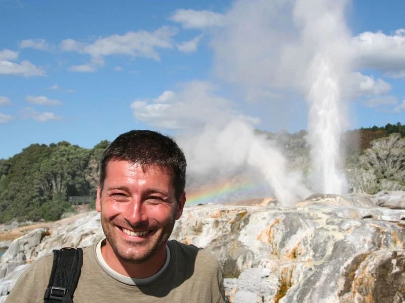 Mann steht vor Geysir in Rotorua, Neuseeland.