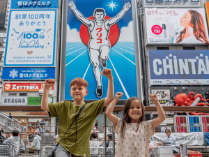 Kinder vor bunter Leuchtreklame in Osaka, Japan